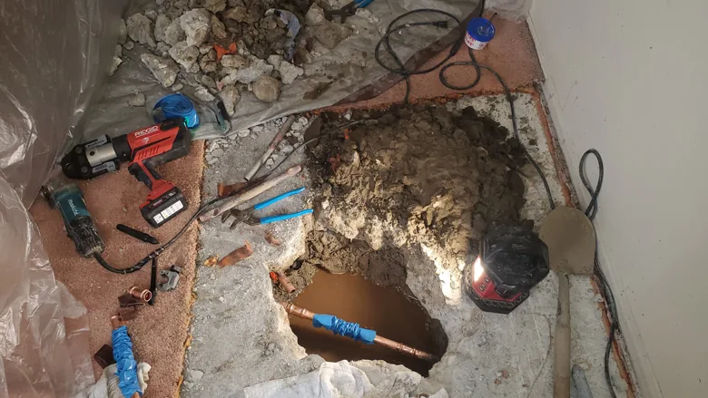 Open slab with exposed pipe and repair tools