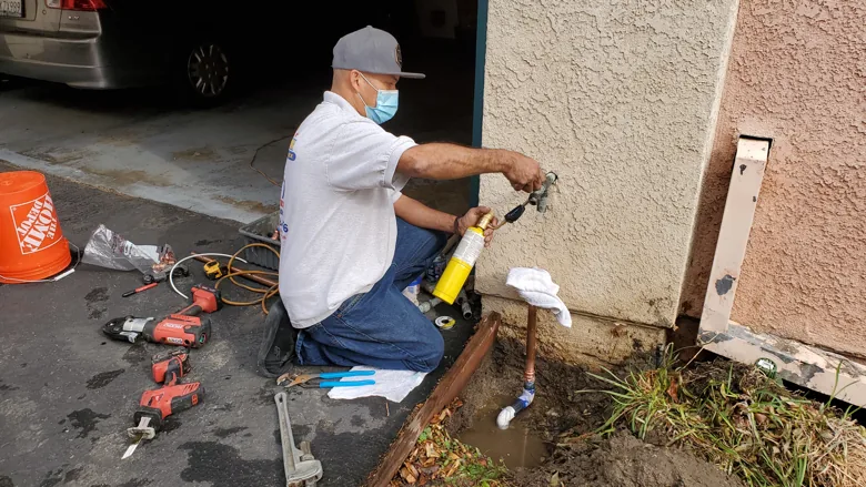 Technician working at an exterior water pipe