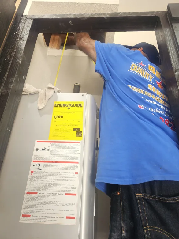 Technician working above a tank water heater in closet