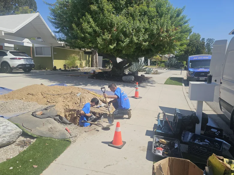 Two technicians at curbside excavation with equipment