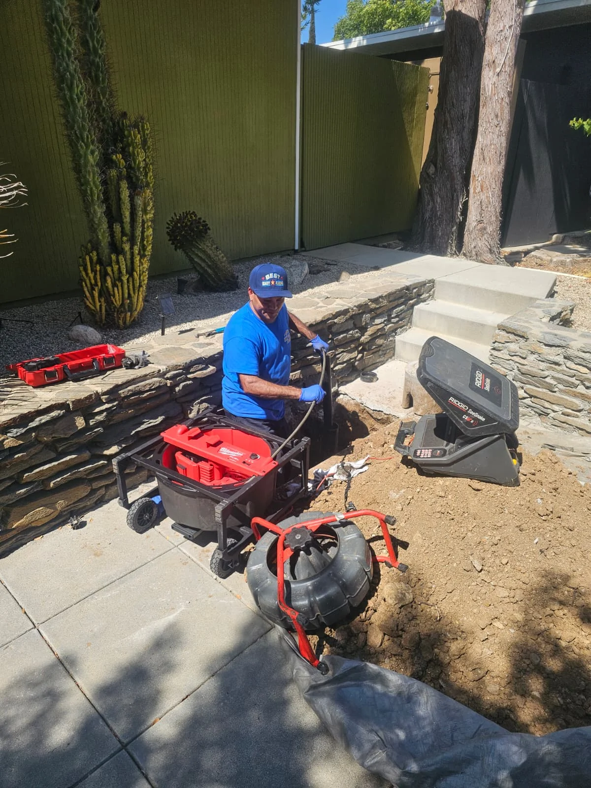 Technician working with drain inspection equipment at an outdoor access point