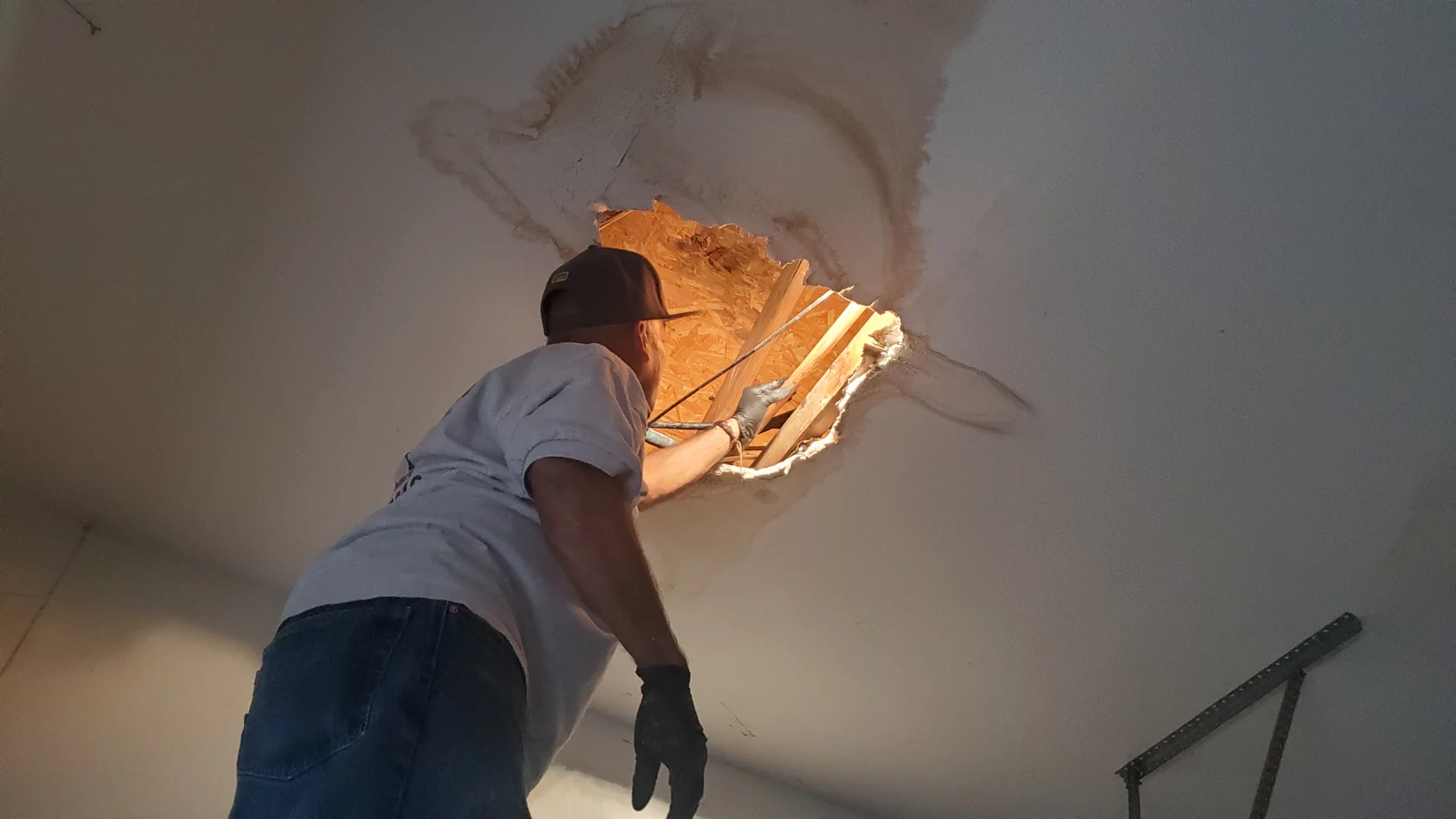 Plumber inspecting plumbing through a ceiling access opening