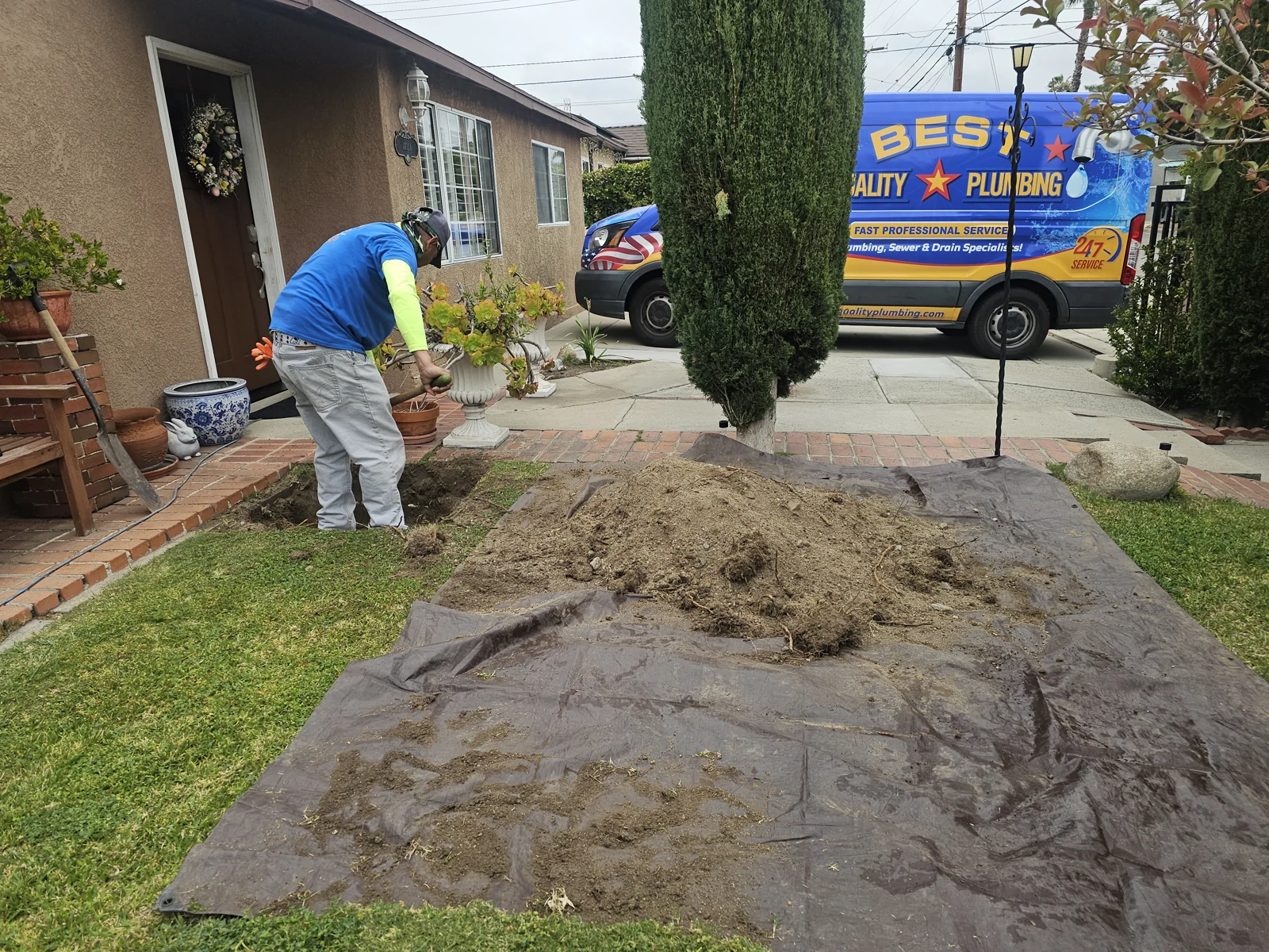 Plumbing crew excavating a residential yard with the company van nearby